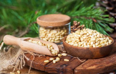 Kasede çam fıstığı, kozalak, dal, kesme tahtasındaki cam kavanoz. Doğal malzemelerden hareketsiz yaşam, yan bakış..