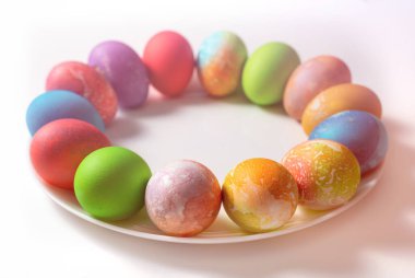 Paskalya için tabakta boyanmış yumurta. Tabak kahverengi bir masada.. 