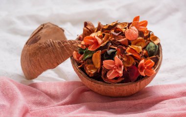 Kurumuş çiçekli hindistan cevizi kasesi ve pembe beyaz kumaşlı tomurcuk yaprakları..