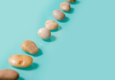 Küçük kahverengi taşlar, çakıl taşlarına benzer, bir turkuaz zemin üzerinde çapraz uzanır..