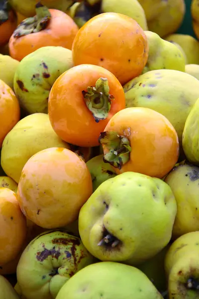 Fresh persimmon and quince on green bakground — Stock Photo, Image