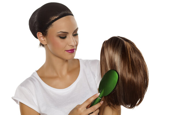 Женщина расчесывает свой парик
