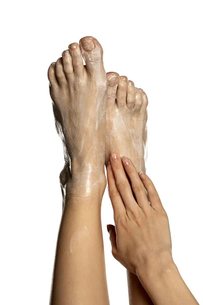 白い背景に彼女の裸の足に足クリームを適用する女性 — ストック写真