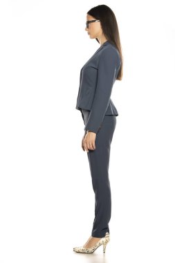 Beyaz arka planda pantolonlu ve ceketli genç ve güzel iş kadınının yan görüntüsü