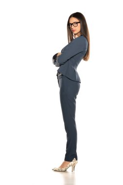 Beyaz arka planda pantolonlu ve ceketli güzel, ciddi bir iş kadınının yan görüntüsü.