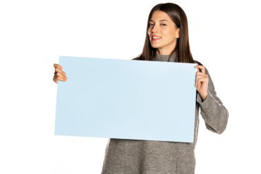 Genç, güzel, mutlu bir kadın beyaz arka planda mavi bir tahta tutuyor.