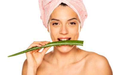 Genç üstsüz kadın beyaz arka planda aloe vera yaprağını ısırıyor.