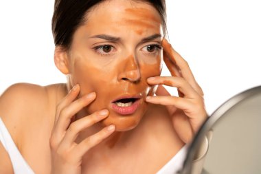 Beyaz arka planda yüzü yanlış makyajlı genç bir kadın.