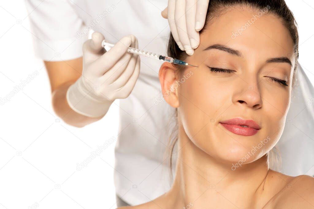 Portrait of a young beautiful woman on a face filler injection procedure on white background