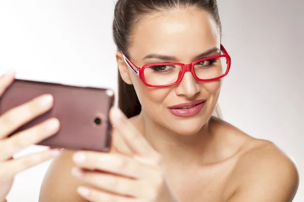 Kvinna med röda glasögon och en telefon — Stockfoto