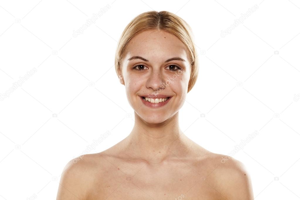 Beleza. close-up de menina bonita e natural com sorriso branco e ombros nus  rindo, sorrindo despreocupado. mulher jovem sem maquiagem mostrando efeito  após cosméticos, parede branca