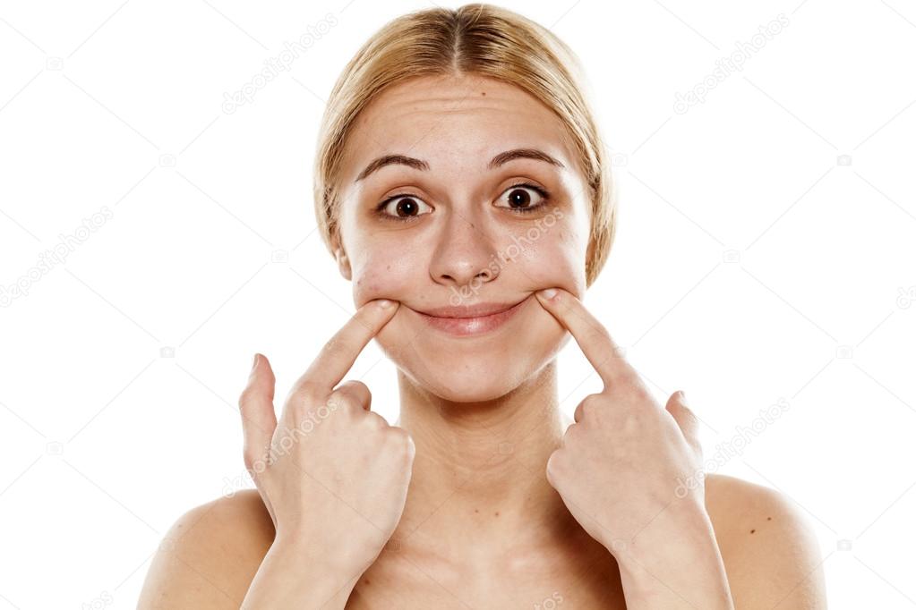 Девушка растягивает рот руками. Разминка для похудения лица. Фиксатор для рта. Человек с напряжённым лицом. Потянул рот.