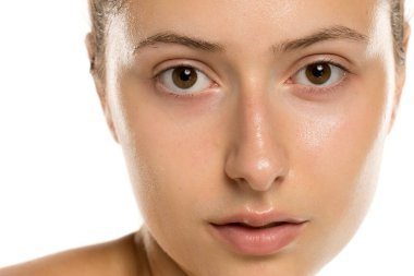 Stüdyo çekiminde genç bir kadının ıslak yüzü, açık gözler ve beyaz arka planda temiz bir ten.