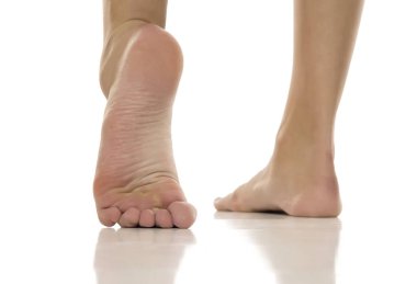 Stüdyoda, beyaz elbiseli, mavi topuklu, tek bacaklı, beyaz arka planda bükülmüş kadınlar poz veriyor..