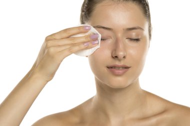 Makyajsız, beyaz arka planda pamuk yastıklı genç bir kadının stüdyo fotoğrafı.