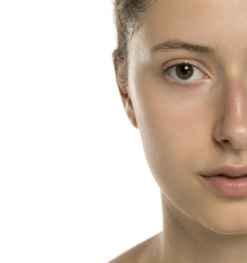 Stüdyo, beyaz arka plandaki makyajın kaldırılmasından sonra genç bir kadının temiz cildine yakın çekim yapıyor.