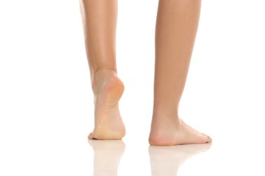 Bir kadının bacak ve ayaklarının arka görüntüsü taban taban, pürüzsüz ciltli parmak uçlarında, beyaz bir arka planda stüdyo çekimi