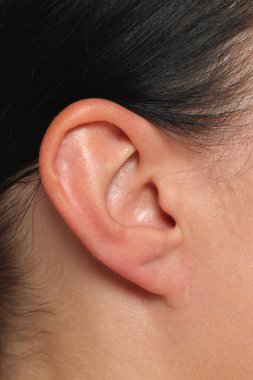 Küpesiz bir kadının kulağı, beyaz arka planda temiz bir doğal ten gösteriyor..