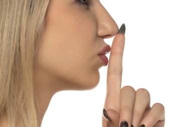 Yan plan, sessiz bir jest yapan bir kadın. Parmağı dudakta, stüdyo resmi beyaz arka planda..