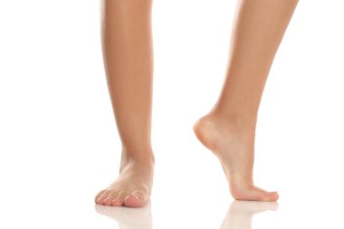 Stüdyo çekimi, beyaz arka planda pürüzsüz bir ciltle ayak parmaklarının ucunda bir kadının ön ve yan görüntüsü.