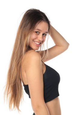 Stüdyo resmi, uzun siyah saçlı, gülümseyen, siyah bluzlu, beyaz arka planda omzunun üzerinden bakan doğal bir kadın..