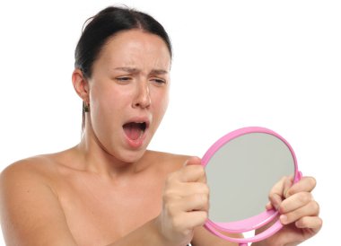 Stüdyo resmi, siyah saçlı, makyajsız, aynasız ve beyaz arka planda şoka uğramış bir kadın.