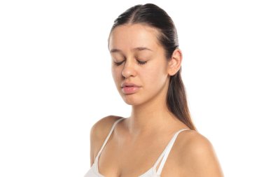 Stüdyo resmi, uzun siyah saçlı, beyaz bluzlu, makyajsız, gözleri kapalı, beyaz arka planda portresi olan doğal bir kadın..