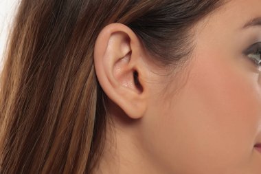 Bir kadının kulaklarının ve saçlarının doğal deri dokusuyla yakın plan görüntüsü, beyaz arka planda stüdyo çekimi..