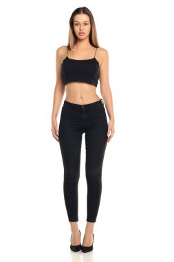 Stüdyo resmi, uzun siyah saçlı, siyah bluzlu, yüksek topuklu, beyaz arka planda, siyah pantolonlu ve topuklu bir kadın..