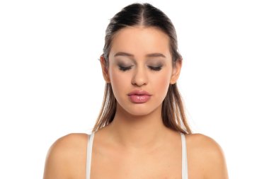 Siyah saçlı, makyajlı, beyaz bluzlu, gözleri kapalı, beyaz arkaplanda portresi olan bir kadının stüdyo fotoğrafı..