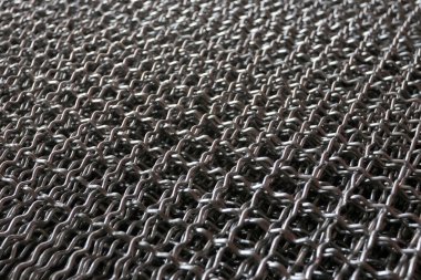 Endüstriyel metal şebeke dokusunu ve inşaat malzemelerini gösteren üst üste yığılmış çelik tel örgülerin yakın çekimi.