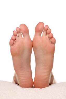 Bir kadının çıplak ayaklarının havluda dinlenen tabanları ve beyaz arka planda çekilen stüdyo fotoğrafları.