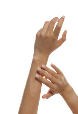 Bir kadının koluna beyaz arka planda kozmetik krem sürerken çekilmiş bir fotoğraf.