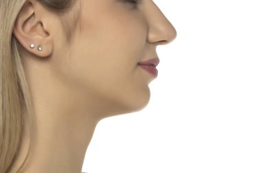 Küçük gümüş küpeler takan bir kadın yüzü ve kulağının yan görüntüsü, beyaz bir arka planda stüdyo çekimi..