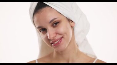 4k video, yavaş çekim, temiz yüzlü genç bir kadının stüdyo çekimi, doğal kaşları ve kafasında havlu, beyaz arka planda makyaj konsepti yok..