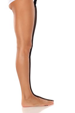 Siyah külotlu çorap giymiş, beyaz stüdyo arka planında düz taban duran bir kadının bacakları görünüyor..