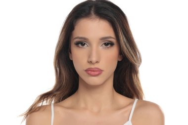 Makyajlı esmer bir kadının beyaz bir arka planda objektif bir ifadeyle, portresiyle, vesikalığıyla doğrudan kameraya baktığı bir fotoğraf..