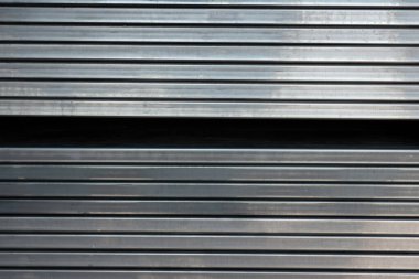 Close-up of stacked square steel hollow section profiles  stored inside an industrial metal warehouse.