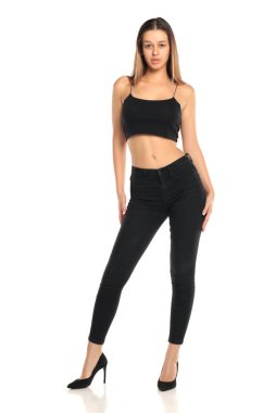 Stüdyo resmi, uzun siyah saçlı, siyah bluzlu, yüksek topuklu, beyaz arka planda, siyah pantolonlu ve topuklu bir kadın..