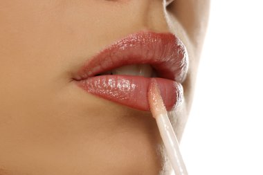 Stüdyo, beyaz arka planda dudaklarına dudak parlatıcısı süren bir kadının yakın plan çekimini yaptı...