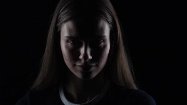 4K sinematik, koyu renk, tüyler ürpertici hareketler yapan genç bir kadının dramatik ışıklandırmada parmağı.