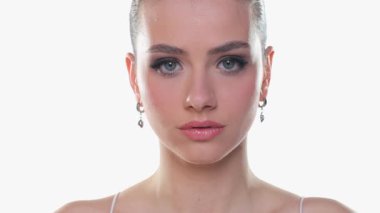 Genç kadın tarafsız yüz, göz kırpan ve gülümseyen, güzellik portresi, beyaz arka planda stüdyo çekimi