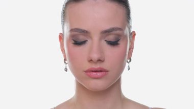 Gözleri kapalı, gülümseyen genç bir kadın. Güzellik portresi, beyaz arka planda stüdyo çekimi.