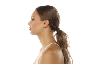 Beyaz kayışlı bluz giyen, kahverengi saçlı, beyaz arka planda stüdyo resmi olan genç bir kadının yan görünümü..