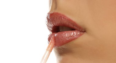 Stüdyo, beyaz arka planda dudaklarına dudak parlatıcısı süren bir kadının yakın plan çekimini yaptı..