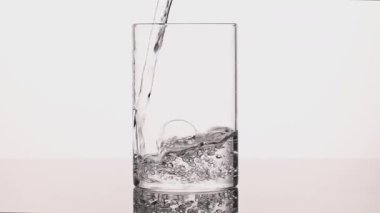 4K yavaş çekim cam temiz içme suyu, kabarcıklar oluşturma ve sıçrama, saf hidrasyon ve sağlıklı yaşam tarzı konsepti, beyaz arka plan üzerine stüdyo çekimi