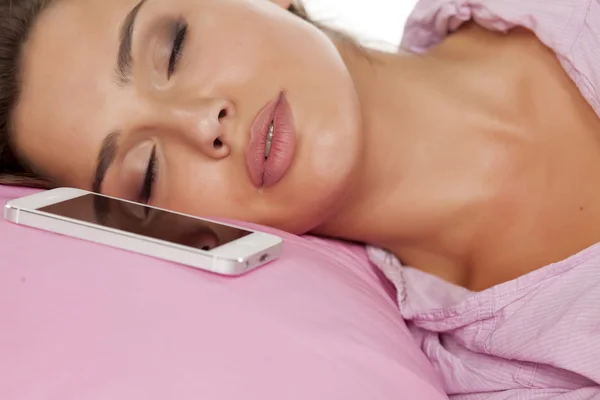 Mulher dormindo com um telefone em sua almofada — Fotografia de Stock