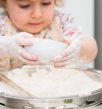 Ufaklık mutfakta un ile pasta fırını yapıyor. Bebek Aşçı Konsepti.