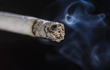 Siyah arkaplanda Dumanlı Sigara Yanar.