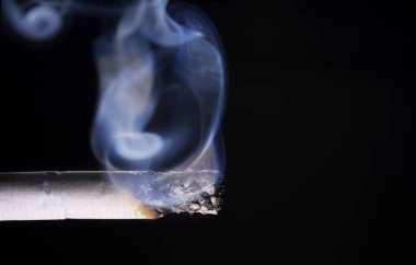 Siyah arkaplanda Dumanlı Sigara Yanar.